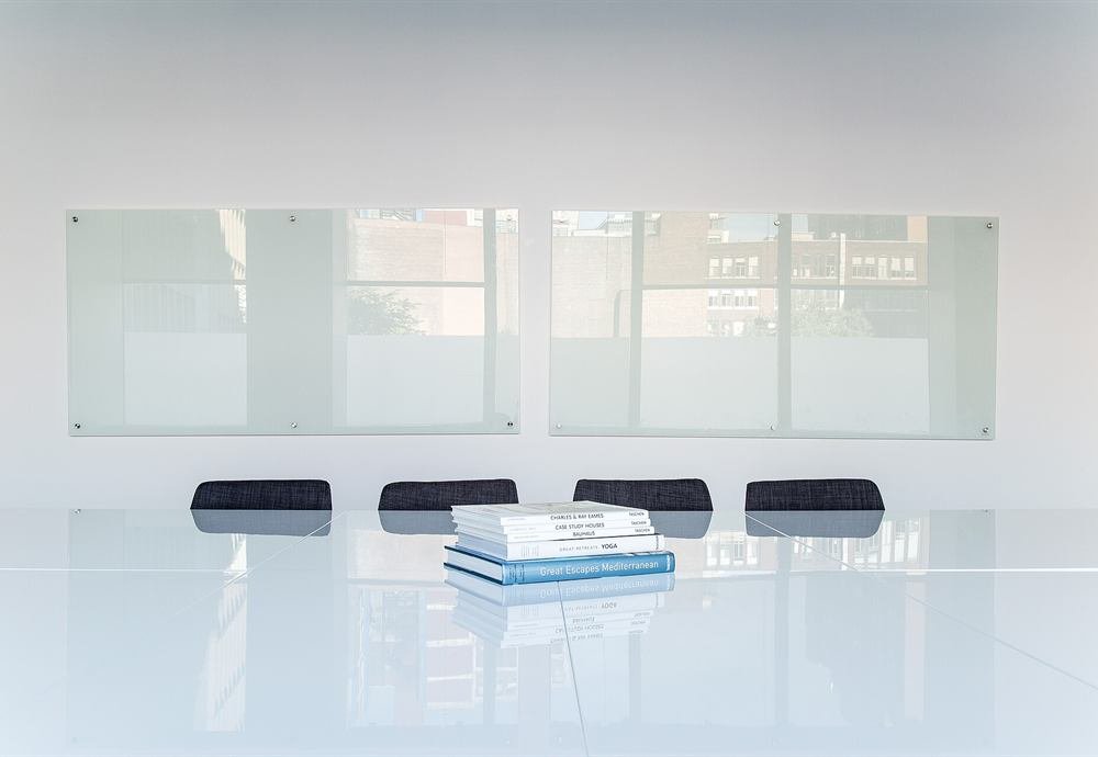 A bright, clean office with a glass table and a whiteboard wall