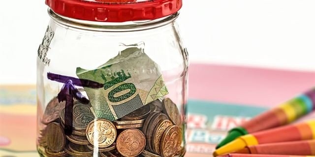 A glass jar of coins and banknotes being saved