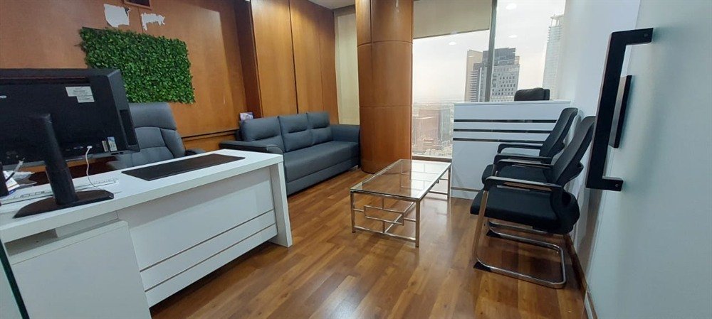 A consultant's office with a desk, sofa and a green wall panel, used for client planning discussions
