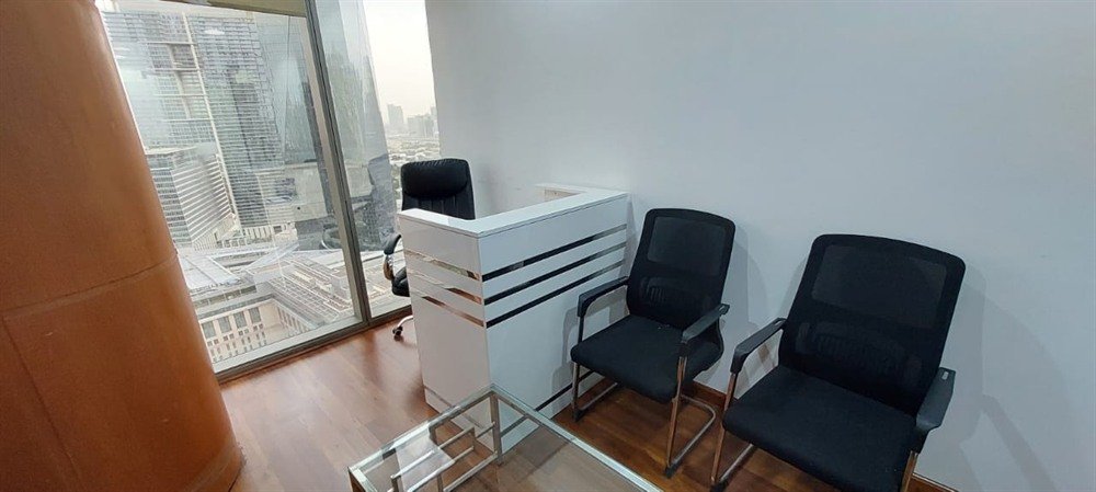 A reception desk and visitor chairs in a consultation office with a window view over Dubai